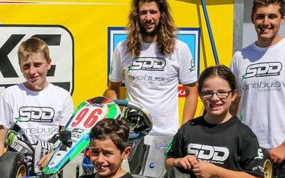 The SDD race team squad in front of a JSKC Racing backdrop with kart number 96