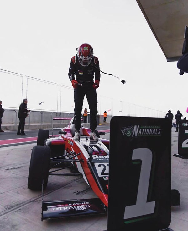 Luis Leeds standing on his single seater race car after a win