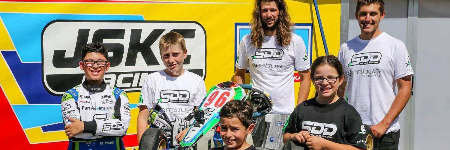 The SDD race team squad in front of a JSKC Racing backdrop with kart number 96