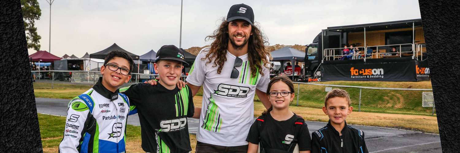 David Sera in Sera Driver Development race gear with five young kart drivers at a race circuit